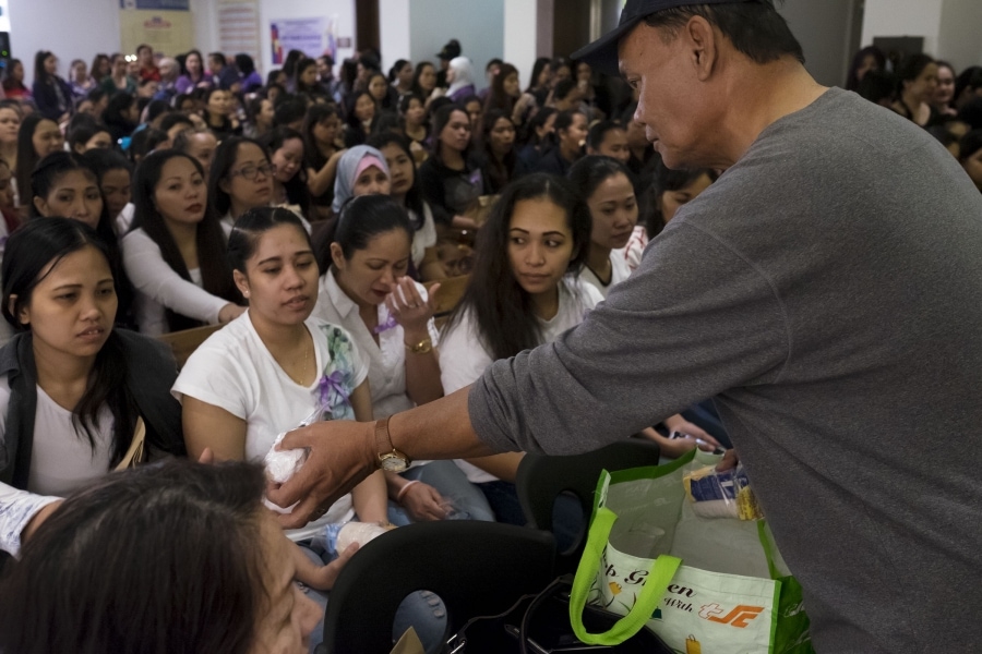 An embassy volunteer hands out meals to Filipina domestic workers who have sought refuge at the embassy after fleeing abusive employers. Credit: Alisa Reznick/PRI
